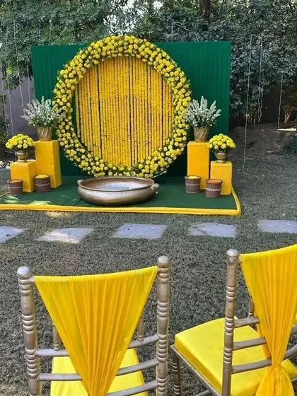 A view of the outdoor Haldi setup from the seating area, showing the decorated chairs in the foreground.