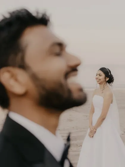 A candid moment of laughter between the bride and groom during their beach photoshoot.