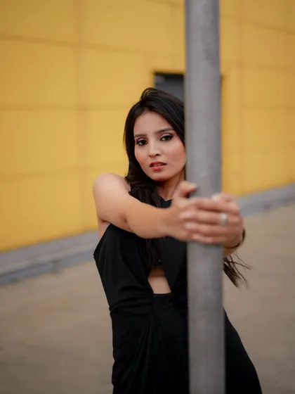 A duplicate of image 469, this portrait against a yellow wall uses a metal pole as a prop to create a modern and graphic fashion shot.