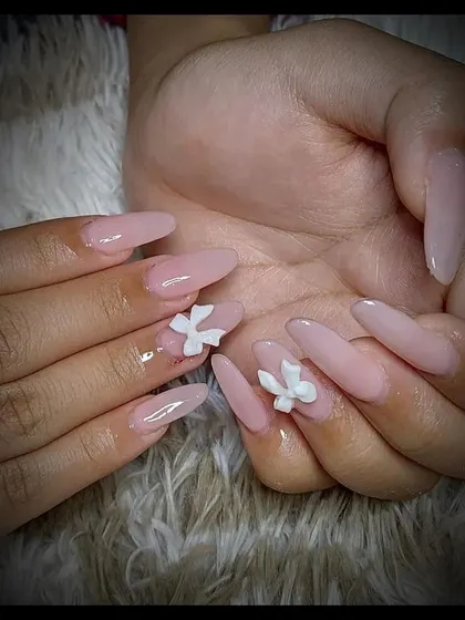 Simple yet elegant nude extensions with 3D white floral accents. This is a great option for clients who want a subtle but beautiful design.
