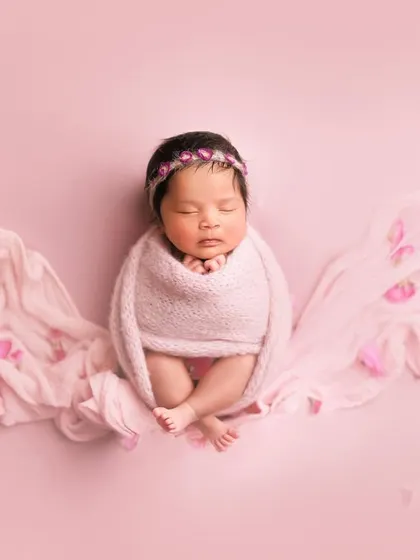 Pretty in pink. This artistic shot uses a flowing pink fabric to create wings, with petals scattered around for a magical, floral effect.