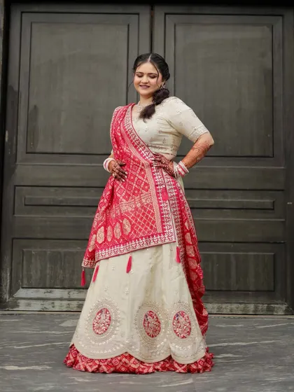 A full-length shot showing the beautiful flow of the ivory and red lehenga. The makeup is designed to complement this elegant and understated bridal style.