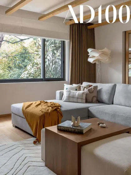 This living room, featured in our AD100 profile, showcases our love for natural light and warm minimalism. The large window frames the lush green view beautifully.
