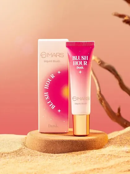This desert-themed shot for Mars Cosmetics' "Blush Hour" uses sand and driftwood to create a warm, natural environment. The composition highlights the product and its packaging against a soft, gradient sunset background.