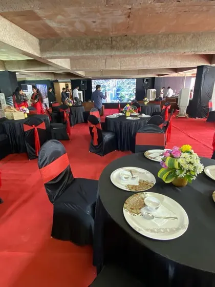 This is the final setup for a real estate sales exhibition, designed to be both professional and welcoming. The layout includes branded banners, formal banquet seating with black and red accents, and a large presentation screen to engage potential clients.