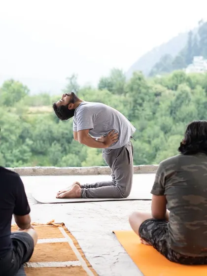 I am demonstrating Ustrasana (Camel Pose) to a group during an outdoor retreat. This heart-opening posture is wonderful for releasing emotional tension and is often practiced with a scenic mountain view.