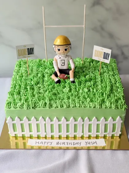 Game day! This rugby-themed cake features a grassy field, a goalpost, and a custom figurine of the birthday boy.