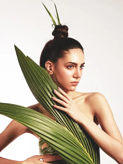 A powerful pose showing the structure of the leaf dress. The hair is pulled up into a sharp top-knot, adding to the architectural feel of the look.
