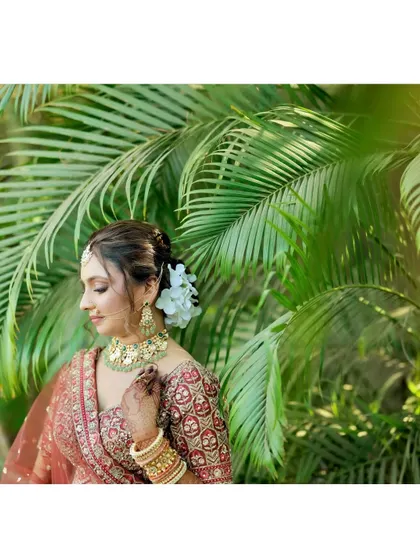 A side profile of the bride, showing the elegant floral hair bun and the subtle contouring that defines her features.