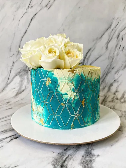 Color can be both modern and elegant. This cake features a beautiful jade green and white watercolor effect on the buttercream, overlaid with a gold geometric stencil pattern and topped with a simple, clean arrangement of fresh white roses.