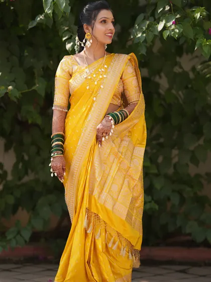 A full-length view of the bride's Haldi look, showcasing her yellow saree and elegant pearl jewellery.