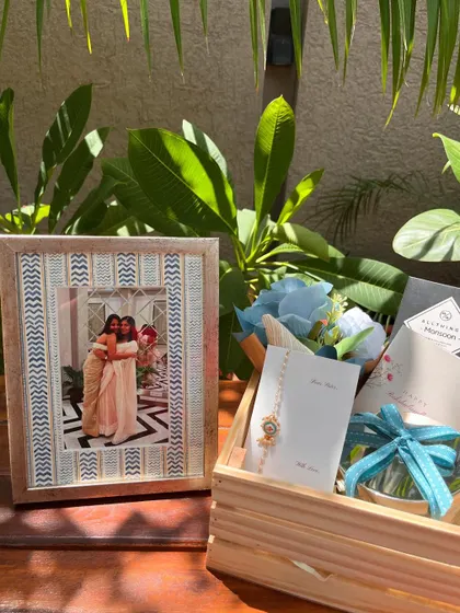 Our Rakhi hamper designed especially for a sister. It includes a beautiful Rakhi, a custom-made photo frame with a cherished picture, a scented candle, and gourmet chocolate, all arranged in a rustic wooden crate.