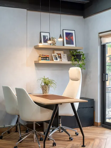 The VP's cabin combines a raw, cemented wall finish with custom wood furniture and floating shelves. The look is simple, sophisticated, and modern.