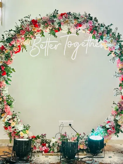 An elegant floral ring for a Roka ceremony. The large ring is covered in beautiful fresh flowers with a "Better Together" neon sign in the center.