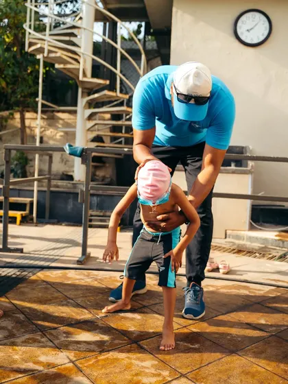 Before hitting the water, we practice key movements on the deck. Here, I'm helping a young student with posture to ensure they are ready for the pool.