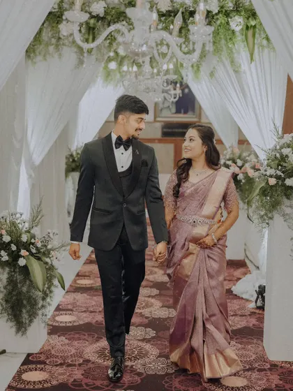 The couple walking hand-in-hand down the aisle at their reception, sharing a happy look.