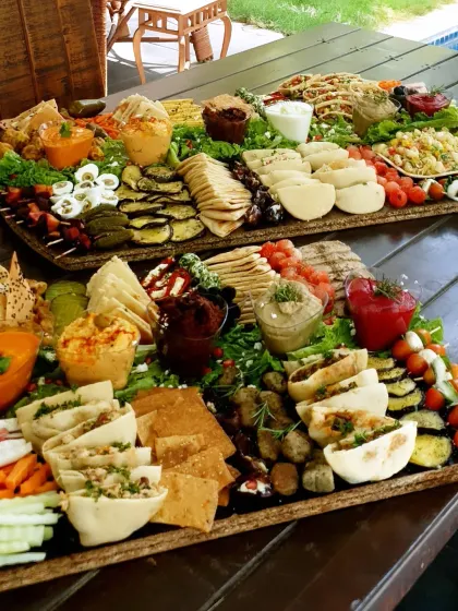 Two of our rectangular boards sit side by side, with crackers, small sandwiches, vegetables and dips arranged for sharing.