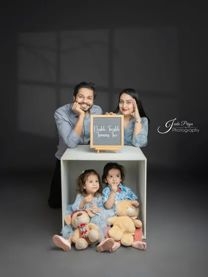 A beautifully composed family portrait with the parents framing the shot and the twins nestled in the box below. This is a great example of a modern family photo.