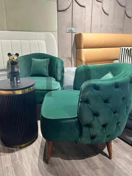 A pair of tufted-back armchairs in a deep emerald green velvet. These chairs are perfect for creating a cozy and luxurious seating nook, offering both comfort and a splash of rich color.