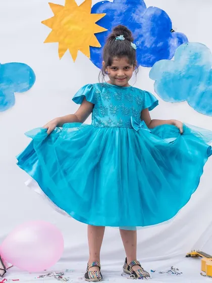 Another angle of this beautiful turquoise party dress, highlighting the full skirt and delicate details on the bodice. It’s a dress that’s sure to make her feel special.
