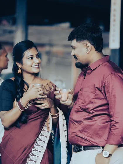 A candid moment of a couple sharing a cup of tea at a market, their traditional attire and the setting creating a warm, retro feel.