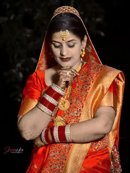 An elegant portrait of a bride in a beautiful orange silk saree, capturing a moment of quiet grace.
