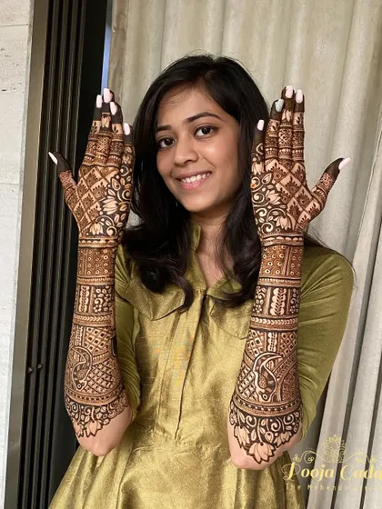 A smiling NRI bride from the US showing off her beautiful, traditional back-hand mehendi design.