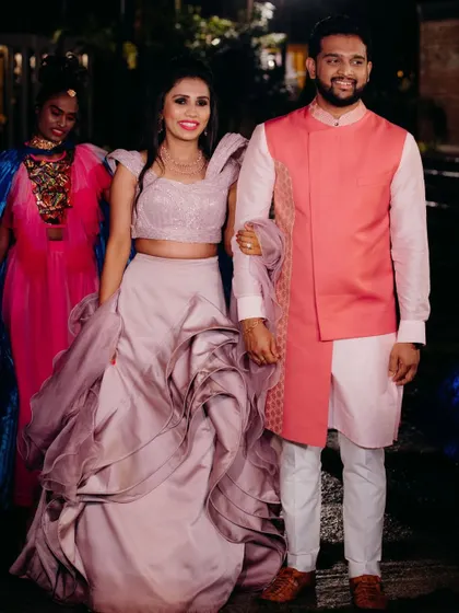 Our bride Varsha and her groom arriving for their sangeet. Her sculpted mauve crop top and skirt pair beautifully with his custom pink jacket and kurta set.