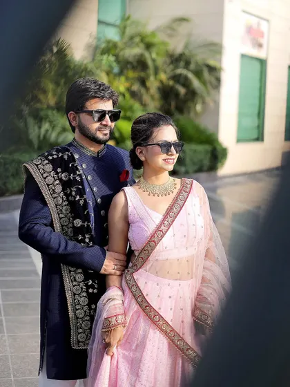 A cool and stylish pre-wedding portrait. The sunglasses add a modern touch to the couple's traditional outfits, showing off their fun personality.