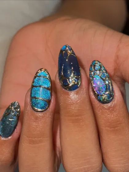 This is what happens when you let me get creative. This set features intricate, hand-painted gold details over a mesmerizing blue cat-eye base on long almond extensions, creating a unique, jewel-like effect.