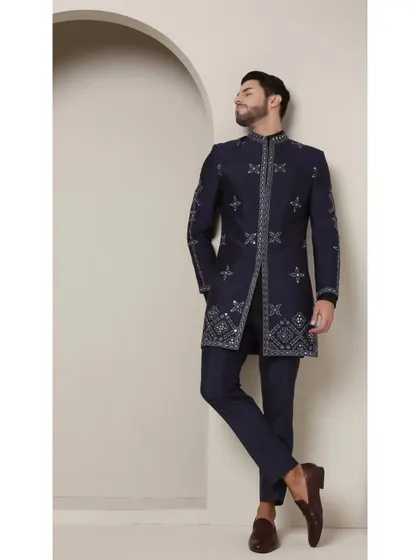 A side profile of the 'Neel Amber' achkan, emphasizing its structured silhouette and the detailed embroidery on the sleeve. This is a garment built on the principles of precision and modern design.