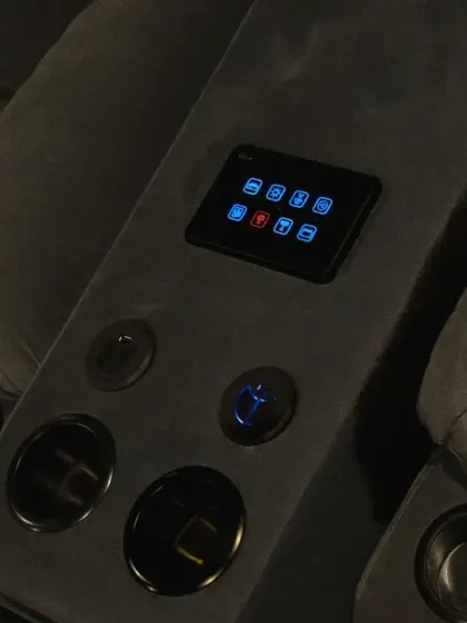 A close-up of the smart panel integrated into the recliner's center console. The matte black finish and illuminated icons add to the high-tech, luxurious feel of the theater.