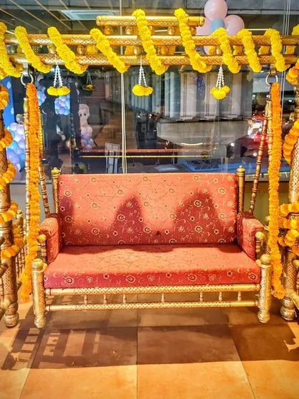 A traditional cradle (jhoola) decorated with marigold garlands for a baby shower.