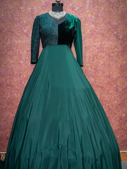 An elegant dark green gown featuring a combination of velvet and sequined fabric on the bodice for a touch of glamour and texture.
