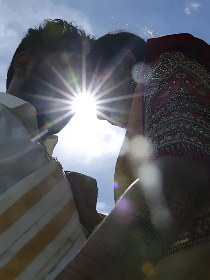 A creative and artistic silhouette of the couple kissing against the sun. The sunburst effect creates a magical and dramatic feel, symbolizing the brightness of their love.