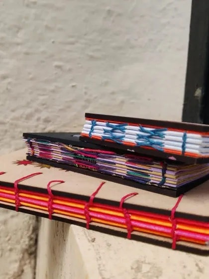 A closer look at the beautiful Coptic stitch binding on these laser cut books, showing off the colorful threads.