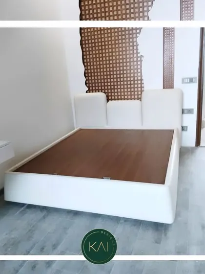 This modern platform bed features a low-profile, asymmetrical headboard in crisp white upholstery. Its minimalist design is perfect for creating a clean and uncluttered bedroom environment.