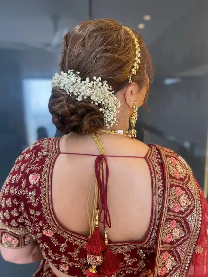 This beautiful bridal messy bun is adorned with a classic arch of white baby's breath, a timeless and elegant choice for any bride.