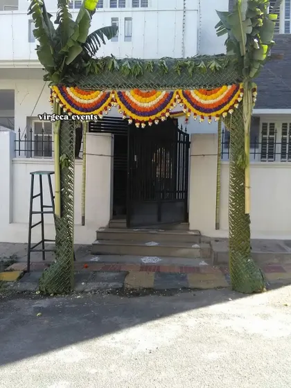 A traditional Chapra entrance gate made from woven coconut leaves and decorated with flowers, perfect for welcoming guests to a housewarming.