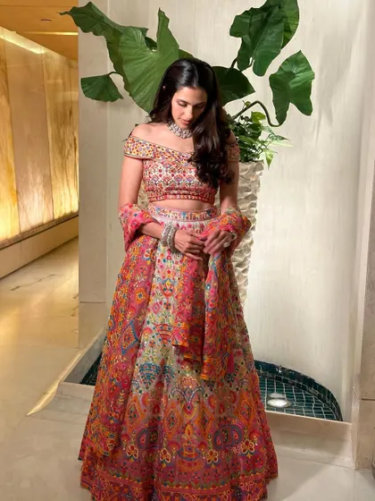 The full view of the colorful Abu Jani Sandeep Khosla lehenga. The off-shoulder blouse adds a modern touch to the traditional printed skirt.