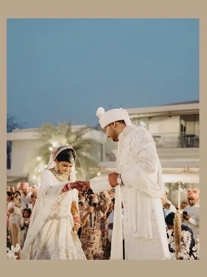 A romantic moment during the Varmala ceremony, set against a beautiful twilight sky.