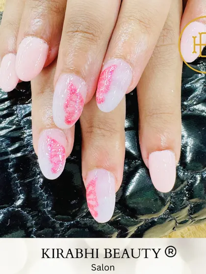 A delicate and artistic design featuring a feather-like pattern in pink glitter on a milky white base. The other nails are a solid soft pink.