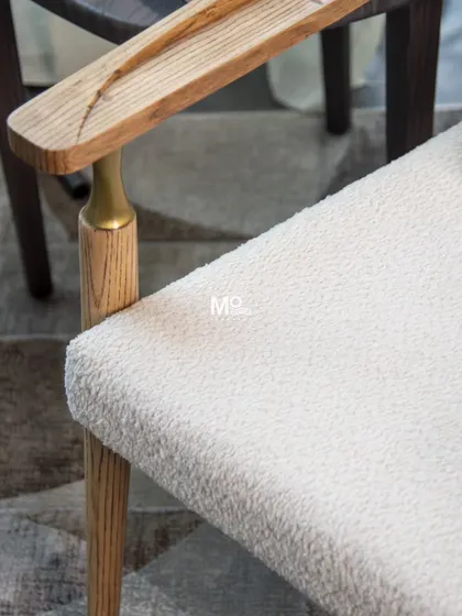 This detail of the Grainline armchair highlights the junction of the solid teak armrest and leg, accented with a brass-toned detail. It shows our commitment to crafting furniture that is not just elegant, but enduring.