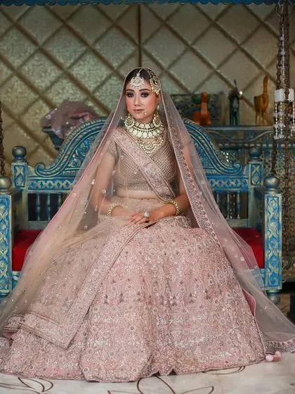 A wide shot capturing the full grandeur of the pink bridal lehenga, with the model framed by traditional puppets for a culturally rich setting.