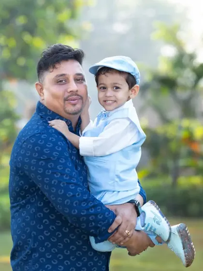 A proud father holds his son, who is dressed in an adorable light blue suit and cap. A heartwarming portrait of a father and his little man.