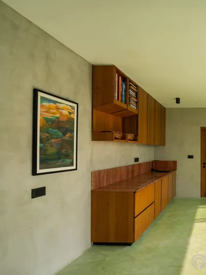 A vibrant green oxide floor flows through this space, complemented by custom wooden cabinetry. The contrast between the smooth, colorful floor and the warm grain of the wood creates a unique and energetic interior.