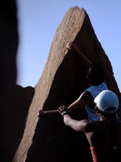 Another angle of the Left Arete climb in Hampi, showing the trust between the climber and her spotter. This connection is fundamental to how we approach climbing and community.
