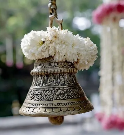 A close-up of a traditional brass bell adorned with white flowers.