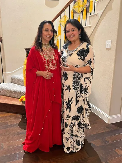 Here I am with a happy client. I'm wearing a red embroidered outfit with a statement necklace, and she looks lovely in a printed kaftan-style dress with elegant earrings.