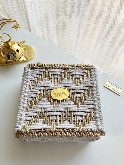 The exterior of the beautiful hand-woven Ramadan gift box, featuring a gold and silver thread design and a "Ramadan Mubarak" tag.